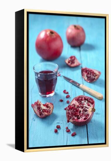 Whole and Sliced Pomegranate and Glass of Pomegranate Juice on Turquoise Wooden Table-Jana Ihle-Framed Premier Image Canvas