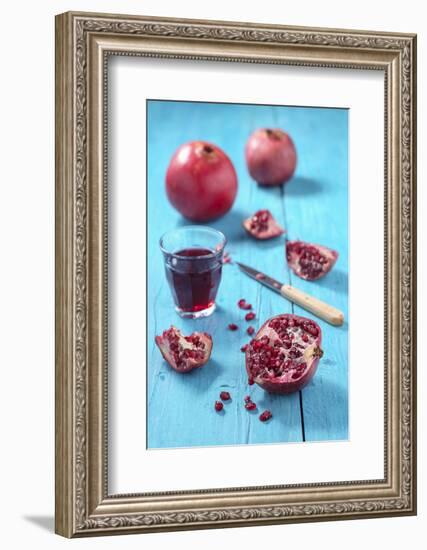 Whole and Sliced Pomegranate and Glass of Pomegranate Juice on Turquoise Wooden Table-Jana Ihle-Framed Photographic Print