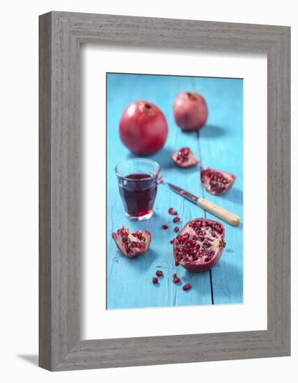 Whole and Sliced Pomegranate and Glass of Pomegranate Juice on Turquoise Wooden Table-Jana Ihle-Framed Photographic Print