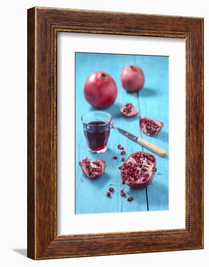 Whole and Sliced Pomegranate and Glass of Pomegranate Juice on Turquoise Wooden Table-Jana Ihle-Framed Photographic Print