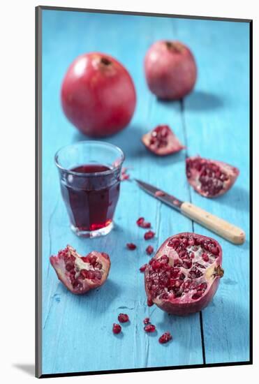 Whole and Sliced Pomegranate and Glass of Pomegranate Juice on Turquoise Wooden Table-Jana Ihle-Mounted Photographic Print