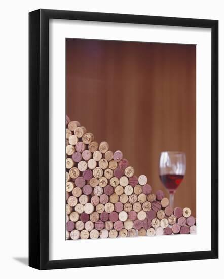 Wine Corks, Piled Up, and a Glass of Red Wine-Henrik Freek-Framed Photographic Print