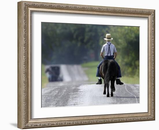 With a Buggy Approaching in the Distance, an Amish Boy Heads Down a Country Road on His Pony-Amy Sancetta-Framed Photographic Print