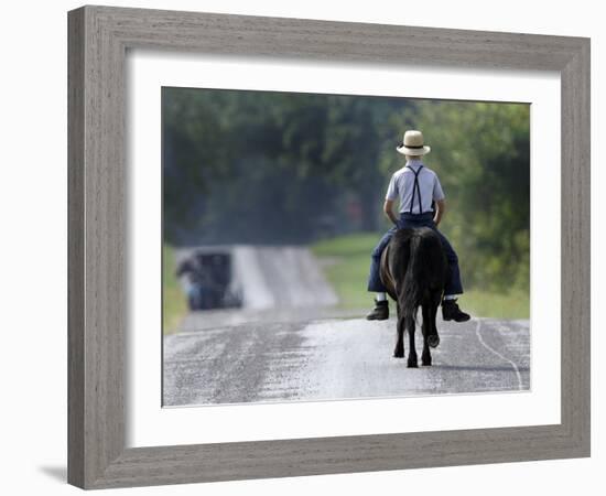 With a Buggy Approaching in the Distance, an Amish Boy Heads Down a Country Road on His Pony-Amy Sancetta-Framed Photographic Print