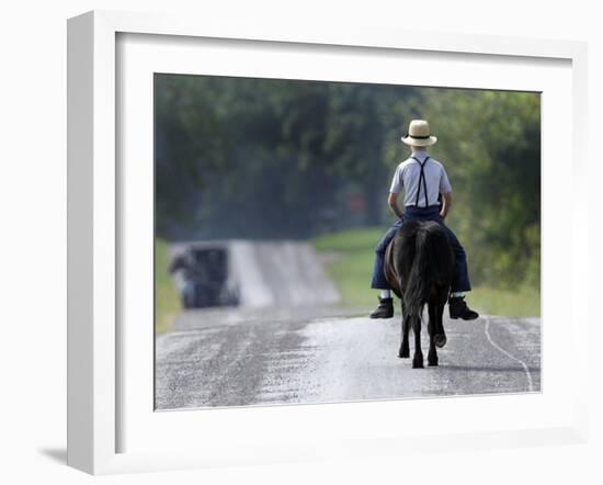 With a Buggy Approaching in the Distance, an Amish Boy Heads Down a Country Road on His Pony-Amy Sancetta-Framed Photographic Print