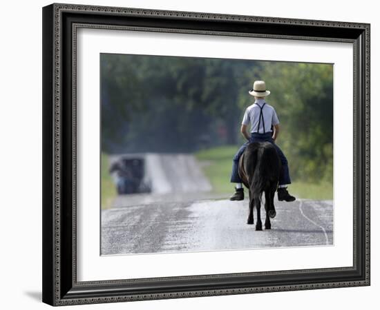 With a Buggy Approaching in the Distance, an Amish Boy Heads Down a Country Road on His Pony-Amy Sancetta-Framed Photographic Print