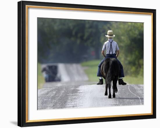 With a Buggy Approaching in the Distance, an Amish Boy Heads Down a Country Road on His Pony-Amy Sancetta-Framed Photographic Print