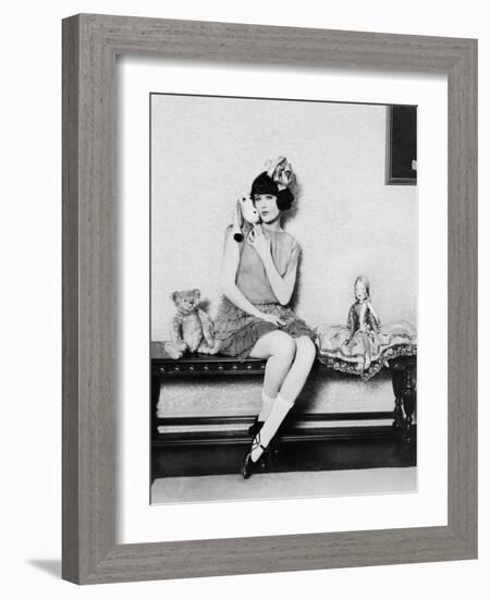 Woman Acting Like a Little Girl Sitting with Toys on a Bench-null-Framed Photo