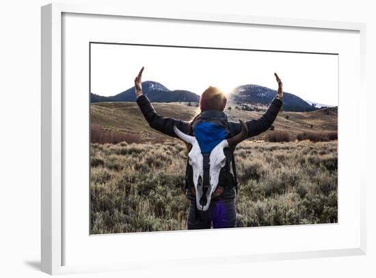 Woman Holds Her Arms Up Like Horns While Wearing A Bison Skull On Her Backpack-Hannah Dewey-Framed Photographic Print