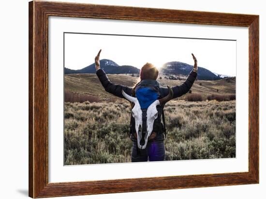 Woman Holds Her Arms Up Like Horns While Wearing A Bison Skull On Her Backpack-Hannah Dewey-Framed Photographic Print