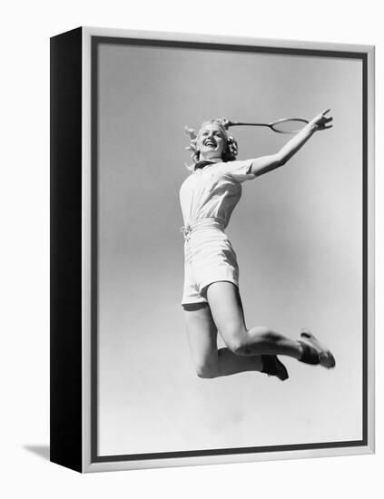 Woman Jumping into the Air with a Tennis Racket in Her Hand-null-Framed Stretched Canvas