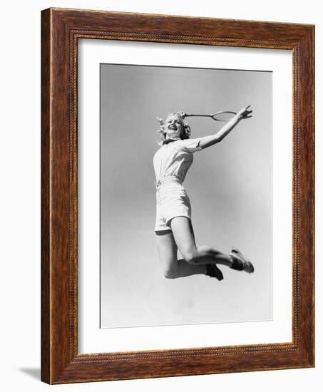 Woman Jumping into the Air with a Tennis Racket in Her Hand-null-Framed Photo