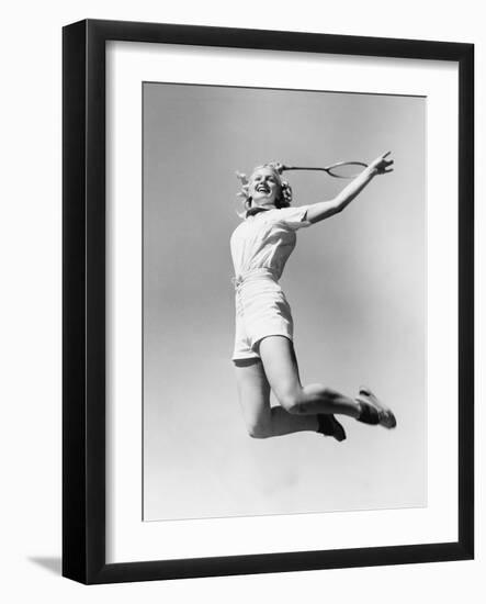 Woman Jumping into the Air with a Tennis Racket in Her Hand-null-Framed Photo