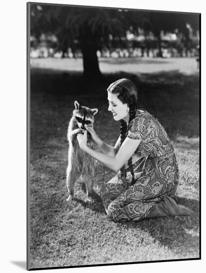Woman Kneeling on the Lawn Playing with a Tame Raccoon-null-Mounted Photo