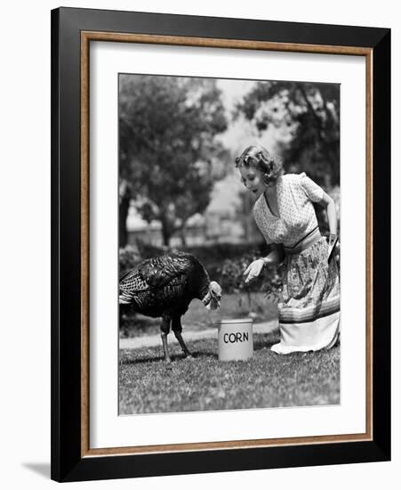 Woman Luring Turkey to Hatchet with Corn-null-Framed Photo