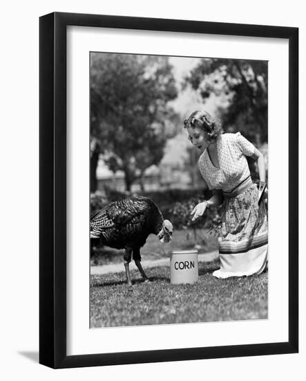 Woman Luring Turkey to Hatchet with Corn-null-Framed Photo