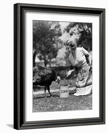 Woman Luring Turkey to Hatchet with Corn-null-Framed Photo