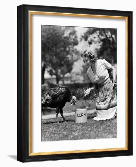 Woman Luring Turkey to Hatchet with Corn-null-Framed Photo