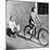 Woman on a Bicycle Pulling a Grown Man on a Toy Tricycle-null-Mounted Photo
