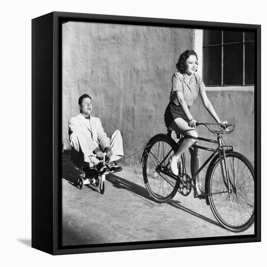 Woman on a Bicycle Pulling a Grown Man on a Toy Tricycle-null-Framed Stretched Canvas