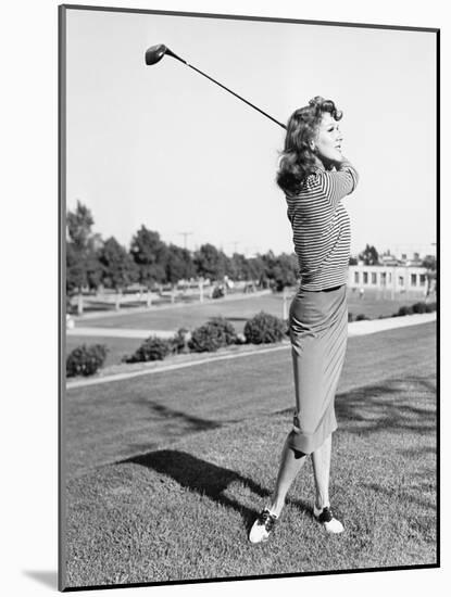 Woman on the Driving Range Swinging a Golf Club-null-Mounted Photo