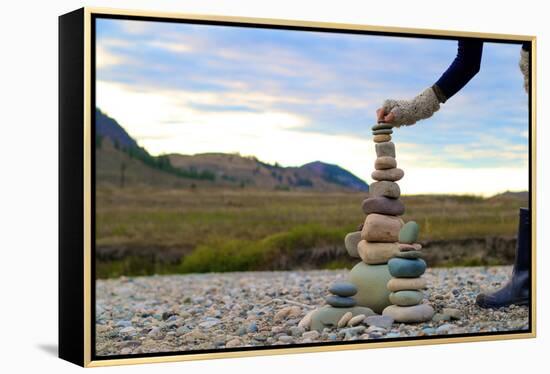 Woman Places A Final Rock Onto A Tall Rock Cairn-Hannah Dewey-Framed Premier Image Canvas