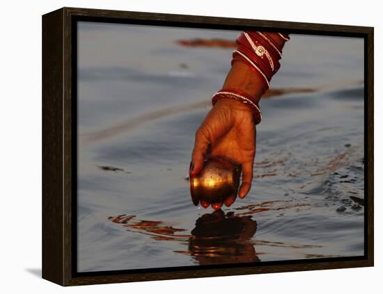 Woman Praying on the Banks of the River Ganges Fills Water into a Copper Vessel for a Ritual-null-Framed Premier Image Canvas