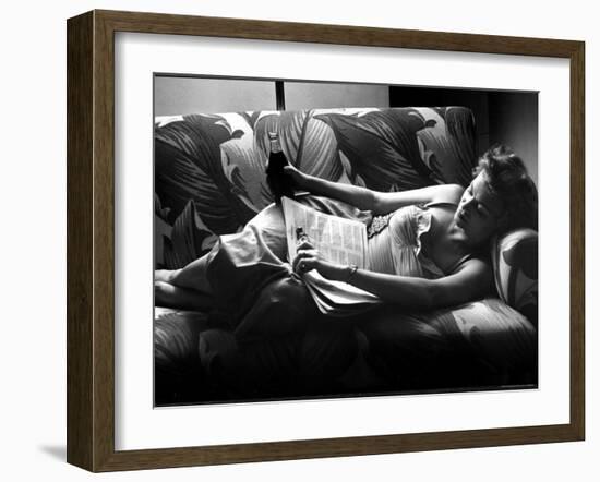 Woman Relaxing on Sofa, Reading and Drinking a Coke-Nina Leen-Framed Photographic Print