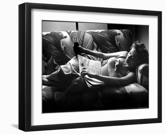 Woman Relaxing on Sofa, Reading and Drinking a Coke-Nina Leen-Framed Photographic Print