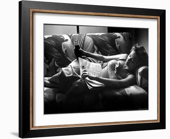 Woman Relaxing on Sofa, Reading and Drinking a Coke-Nina Leen-Framed Photographic Print