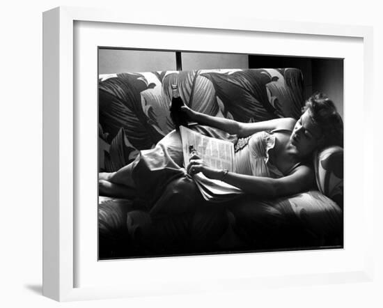 Woman Relaxing on Sofa, Reading and Drinking a Coke-Nina Leen-Framed Photographic Print