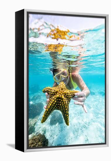 Woman showing a yellow starfish underwater in the tropical lagoon, Zanzibar, Tanzania-Roberto Moiola-Framed Premier Image Canvas