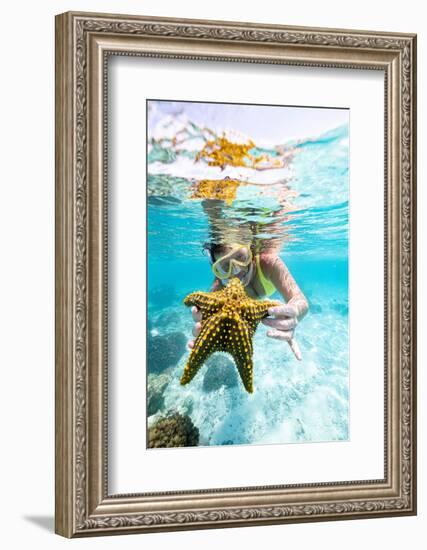 Woman showing a yellow starfish underwater in the tropical lagoon, Zanzibar, Tanzania-Roberto Moiola-Framed Photographic Print