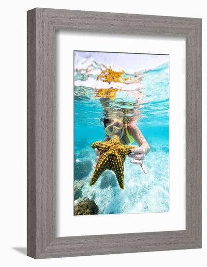 Woman showing a yellow starfish underwater in the tropical lagoon, Zanzibar, Tanzania-Roberto Moiola-Framed Photographic Print