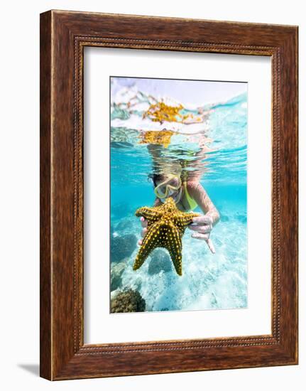 Woman showing a yellow starfish underwater in the tropical lagoon, Zanzibar, Tanzania-Roberto Moiola-Framed Photographic Print