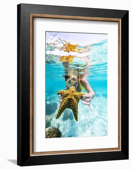 Woman showing a yellow starfish underwater in the tropical lagoon, Zanzibar, Tanzania-Roberto Moiola-Framed Photographic Print