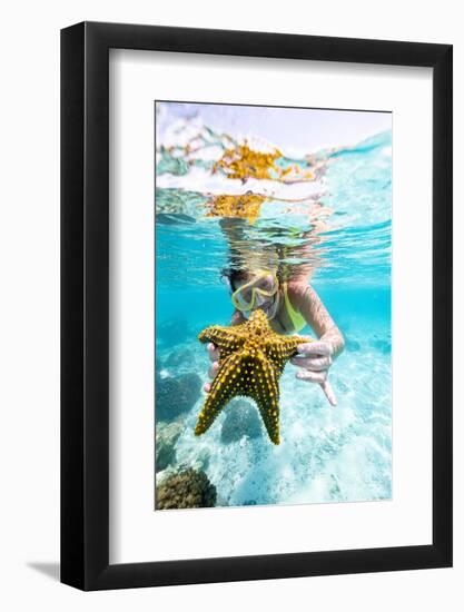 Woman showing a yellow starfish underwater in the tropical lagoon, Zanzibar, Tanzania-Roberto Moiola-Framed Photographic Print