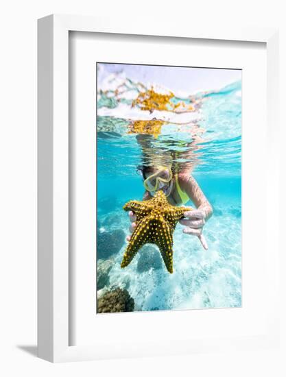 Woman showing a yellow starfish underwater in the tropical lagoon, Zanzibar, Tanzania-Roberto Moiola-Framed Photographic Print