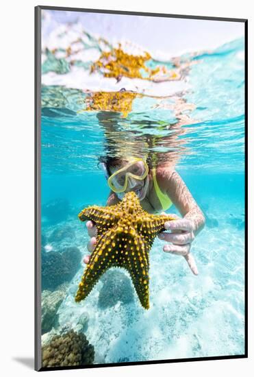 Woman showing a yellow starfish underwater in the tropical lagoon, Zanzibar, Tanzania-Roberto Moiola-Mounted Photographic Print