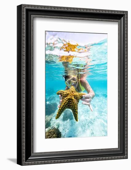 Woman showing a yellow starfish underwater in the tropical lagoon, Zanzibar, Tanzania-Roberto Moiola-Framed Photographic Print