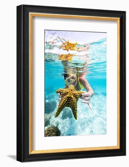 Woman showing a yellow starfish underwater in the tropical lagoon, Zanzibar, Tanzania-Roberto Moiola-Framed Photographic Print