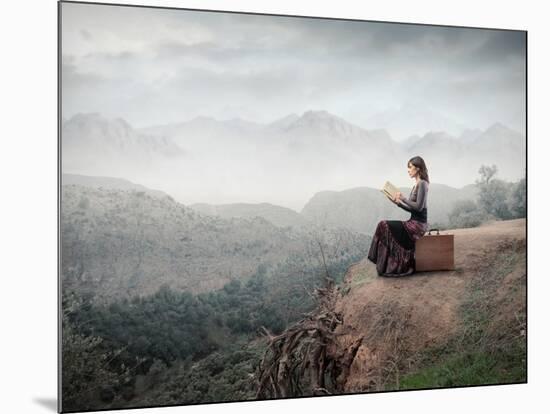 Woman Sitting On A Suitcase And Reading A Book With Landscape On The Background-olly2-Mounted Art Print