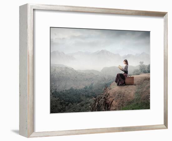 Woman Sitting On A Suitcase And Reading A Book With Landscape On The Background-olly2-Framed Art Print