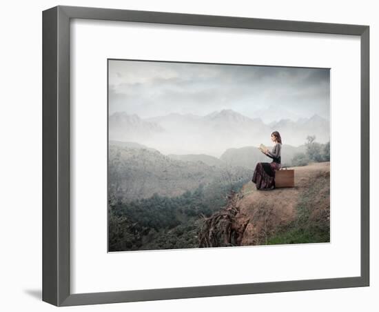 Woman Sitting On A Suitcase And Reading A Book With Landscape On The Background-olly2-Framed Art Print