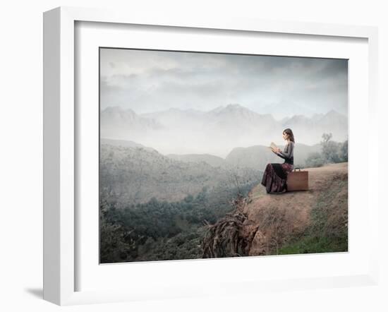 Woman Sitting On A Suitcase And Reading A Book With Landscape On The Background-olly2-Framed Art Print