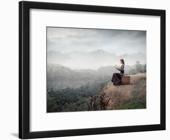 Woman Sitting On A Suitcase And Reading A Book With Landscape On The Background-olly2-Framed Art Print