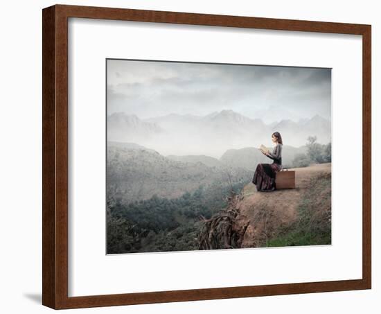 Woman Sitting On A Suitcase And Reading A Book With Landscape On The Background-olly2-Framed Art Print