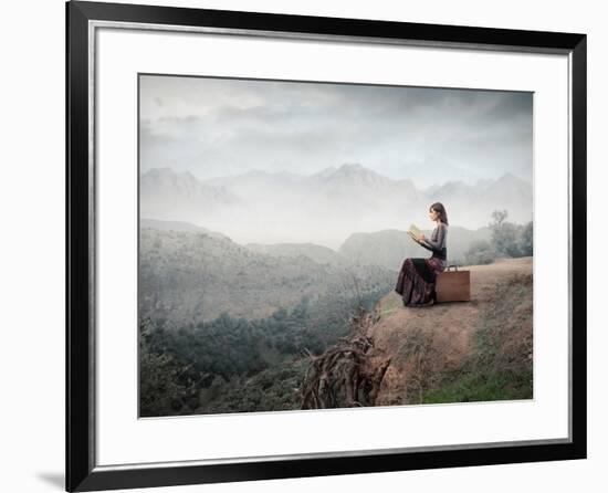 Woman Sitting On A Suitcase And Reading A Book With Landscape On The Background-olly2-Framed Art Print