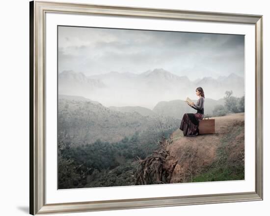 Woman Sitting On A Suitcase And Reading A Book With Landscape On The Background-olly2-Framed Art Print