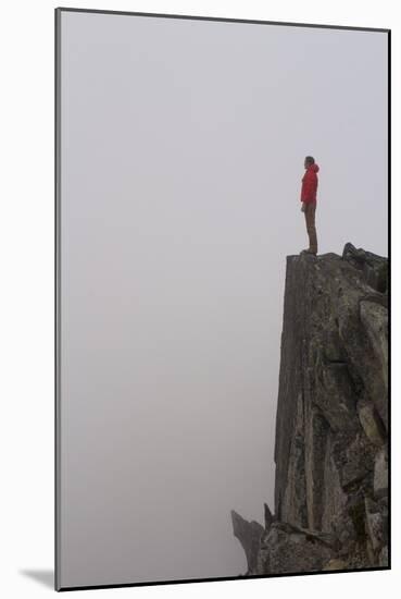 Woman Stands Looking Out Into The Fog On Top Of A Cliff In The North Cascades, Wa-Hannah Dewey-Mounted Photographic Print